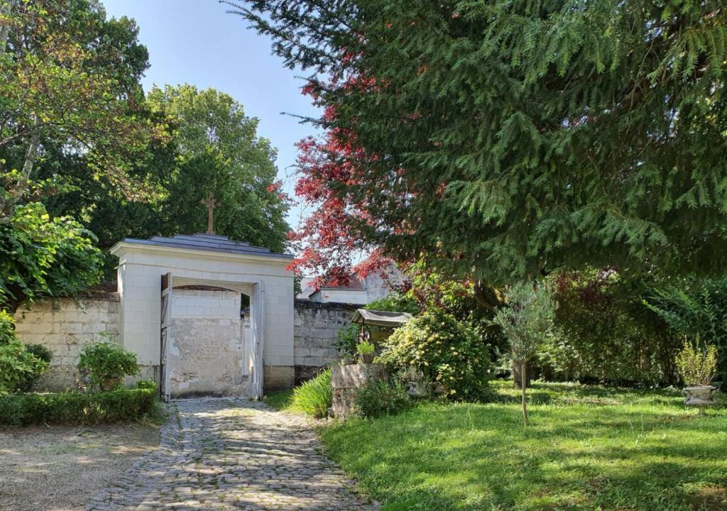 un jardin avec une porte blanche et un arbre dans l'établissement LE PRESBYTÈRE DE LA CITE ROYALE DE LOCHES, à Loches