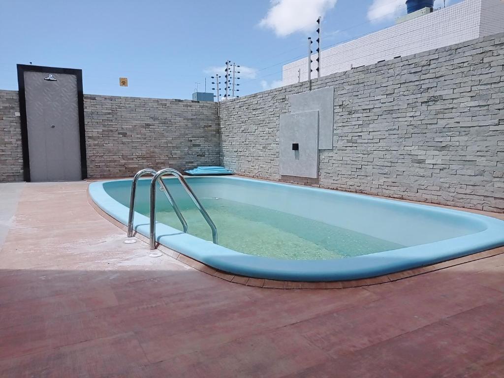un bain à remous sur une terrasse avec un mur en briques dans l'établissement (Bancários) Perto de cabo branco, à João Pessoa