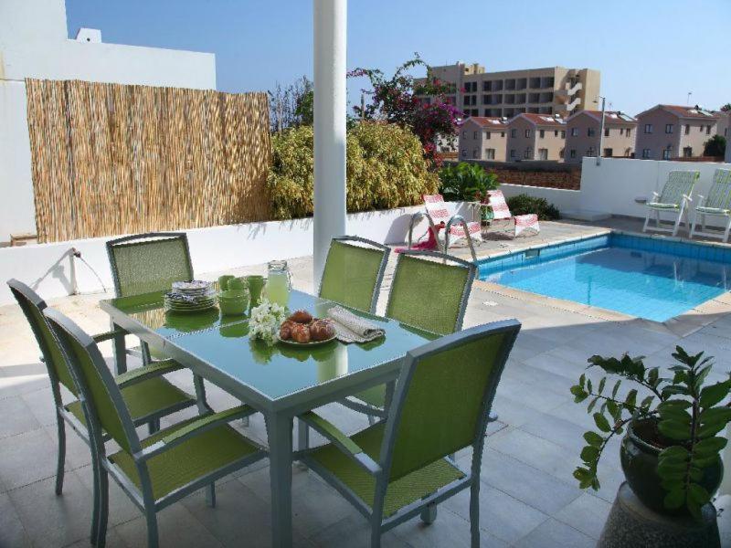 Ein Tisch und Stühle auf einer Terrasse neben einem Pool in der Unterkunft Architect's Villa in Protaras