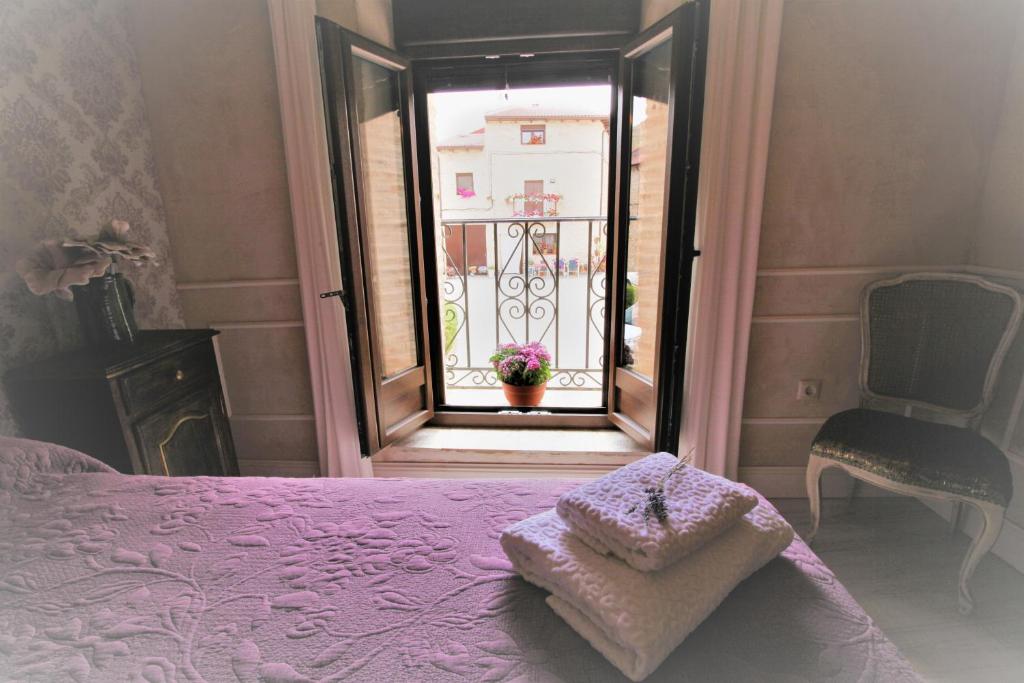 a bedroom with a bed and a window with a chair at Wabisabi Townhouse in Montejo de la Vega de la Serrezuela