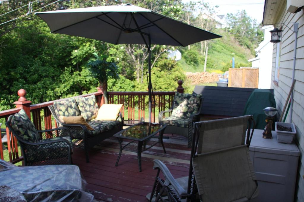 a patio with chairs and an umbrella on a deck at La Maison entre Mer Montagnes in Cap-Chat