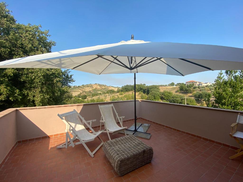 patio z 2 krzesłami i parasolem w obiekcie Casale Cialifone w mieście Alanno