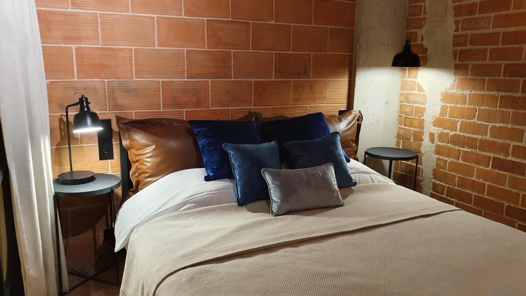 1 cama con almohadas azules y pared de ladrillo en Two-level CATCHY LOFT Alicante Beach & Castle, en Alicante