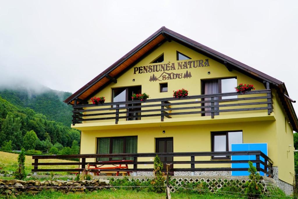 un grande edificio giallo con fiori sul balcone di Pensiunea Natura Sadu a Sibiu
