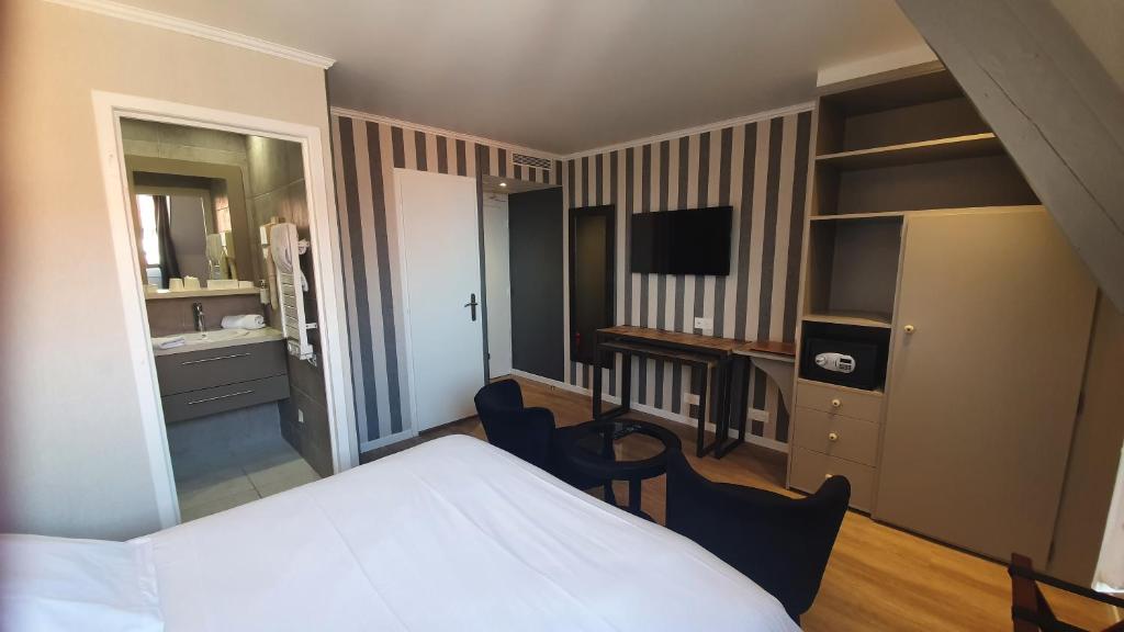 a bedroom with a bed and a desk and a television at Le Trophée Boutique Hôtel Spa- La Loggia Appart'hôtel in Deauville