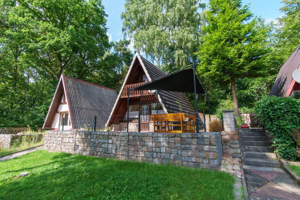 a home with a stone wall and a house at Naturcamping Perlin Ferienhaus in Perlin