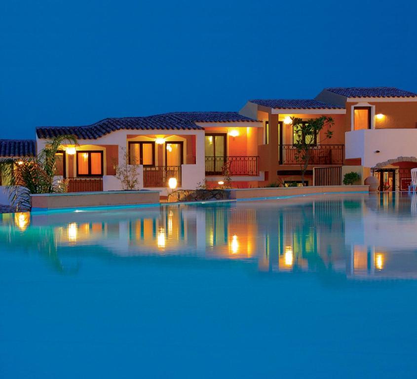una grande piscina di fronte a una casa di notte di iGV Club Santaclara a Porto Pollo