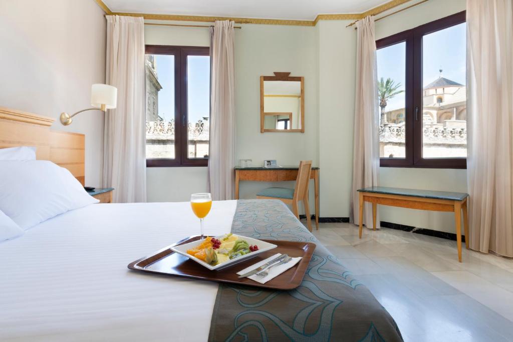 a hotel room with a tray of food on a bed at Eurostars Maimonides in Córdoba