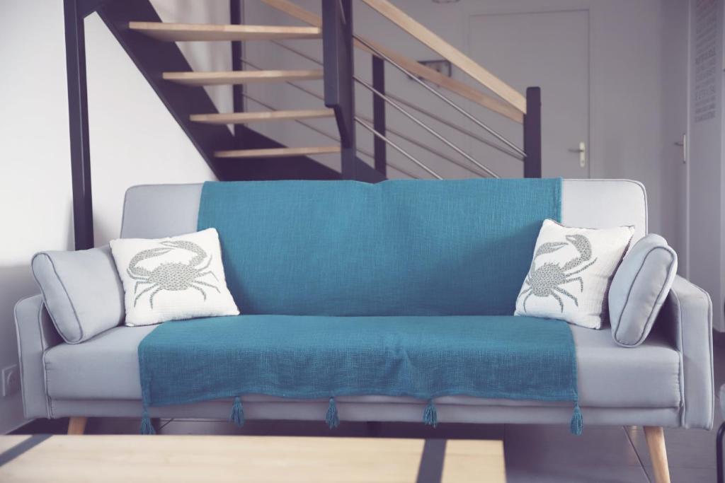 um sofá azul com duas almofadas em cima em Maison neuve à 350m de la plage La casa Sovaïna em Cléder