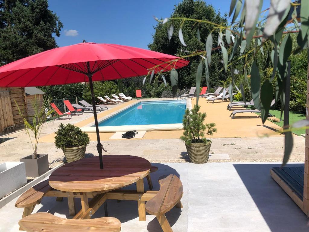 a table with a red umbrella next to a pool at Au Soleil d'Or in Pontaubert