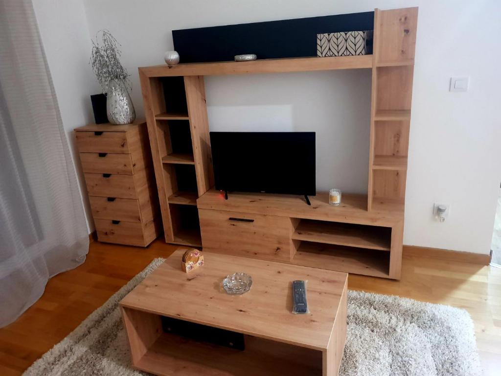 una sala de estar con un centro de entretenimiento de madera con TV en Relax, en Obrenovac