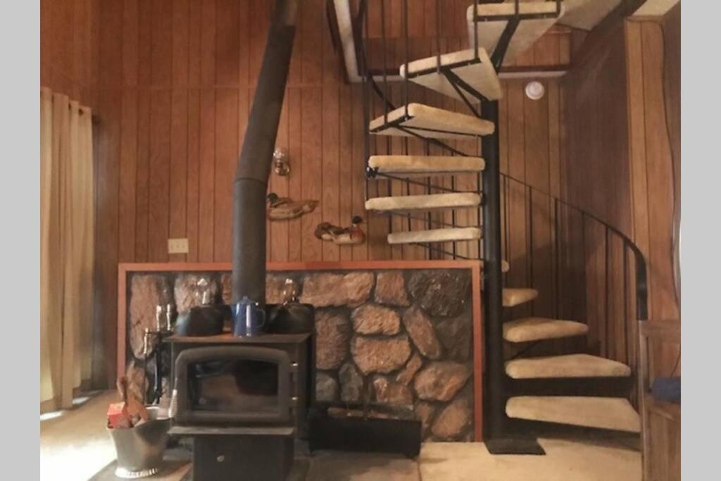 a room with a stone fireplace and a spiral staircase at High Sierra Retreat with a view of Pinecrest lake in Pinecrest