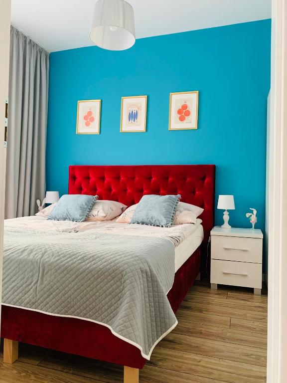 1 dormitorio con cama roja y pared azul en Apartament Walczaka nr 16 MIEJSCE PARKINGOWE, en Gorzów Wielkopolski