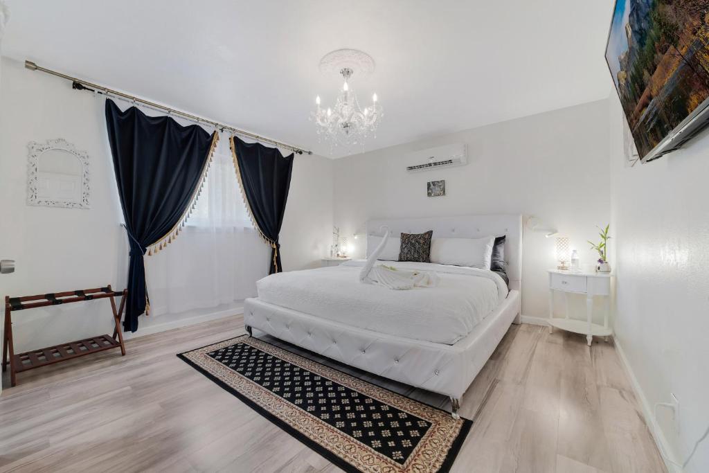 a white bedroom with a large bed and a chandelier at Villa Sierra in Sonora