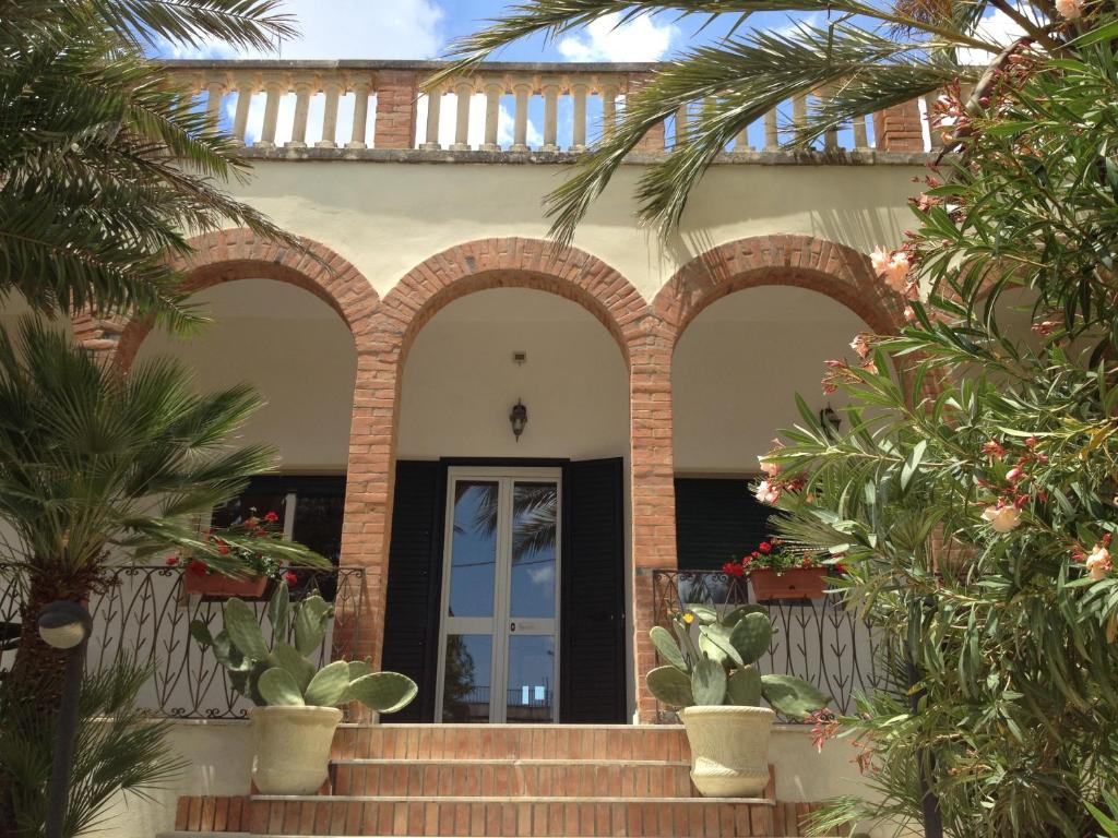 una casa con una puerta y algunas palmeras en Ville Colonia Marina, en Marina di Noto