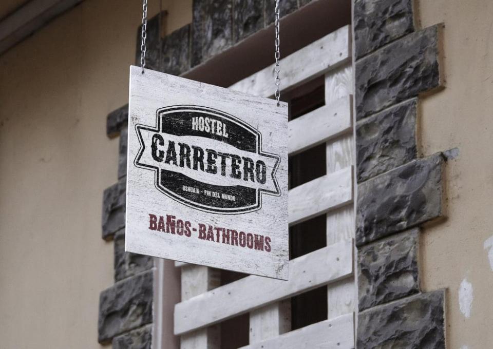 un cartello appeso a un muro di mattoni di fronte a un edificio di El Carretero a Ushuaia