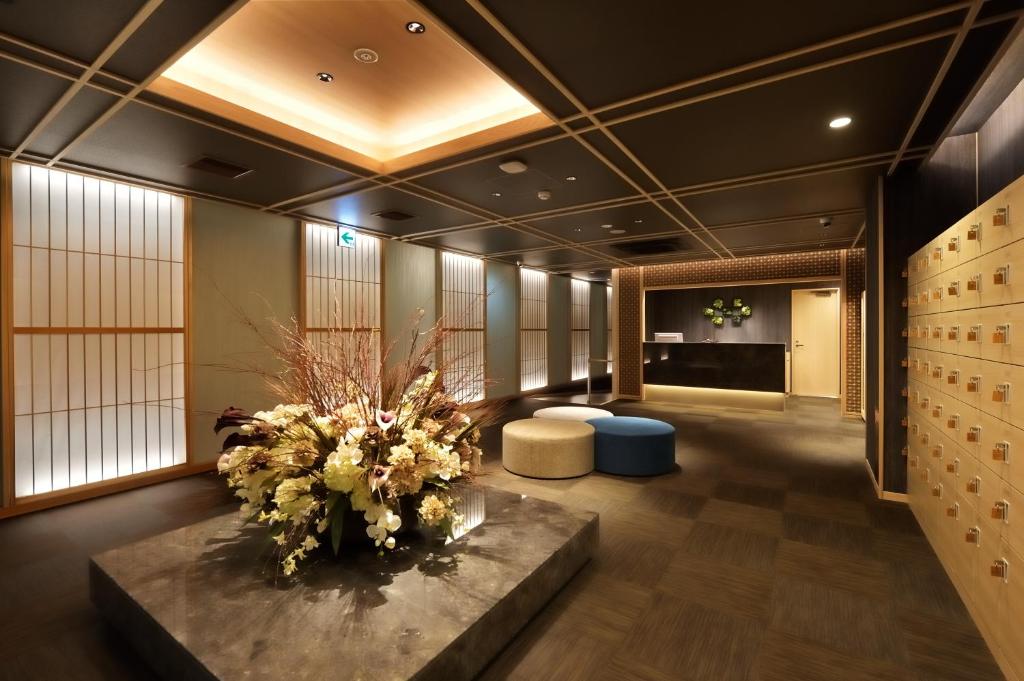 a lobby with a large vase of flowers on a table at Cabin & Capsule Hotel J-SHIP Osaka Namba in Osaka