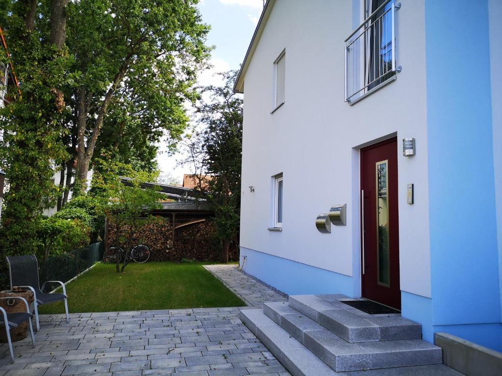 una casa blanca con una puerta roja y un patio en Ferienwohnungen Elsen, en Schwebheim