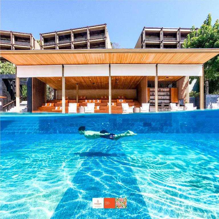 a person laying in the water in a swimming pool at Sunsuri Phuket - SHA Plus in Nai Harn Beach
