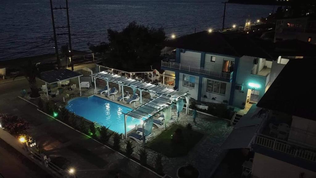 una piscina por la noche junto a un edificio en SUNSET HOTEL en Néos Marmarás