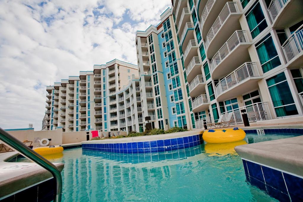 a swimming pool in front of a large apartment building at The Horizon at 77th in Myrtle Beach