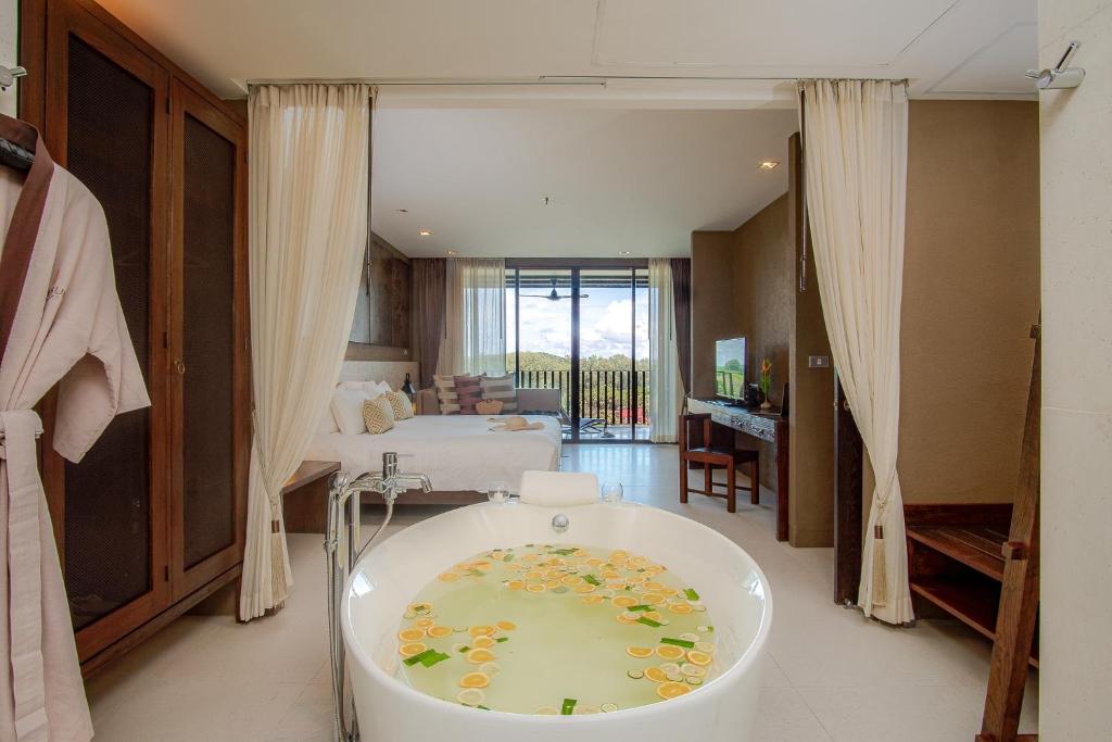 a bathroom with a bath tub in the middle of a room at Sunsuri Phuket - SHA Plus in Nai Harn Beach