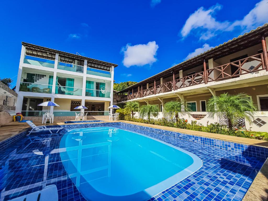 une piscine en face d'un bâtiment dans l'établissement Village Encantado, à Guarajuba