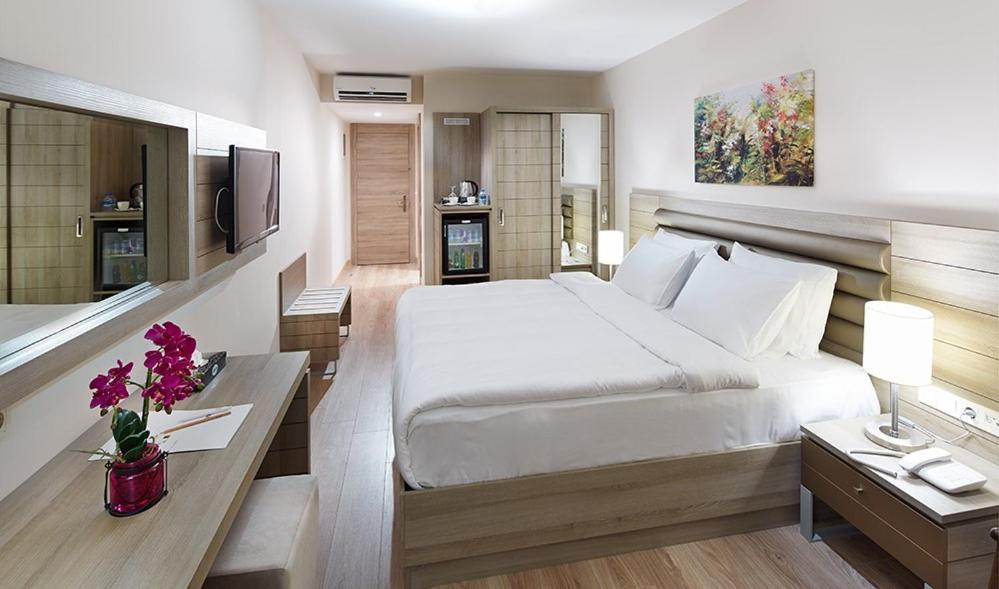 a bedroom with a large white bed and a television at Rox Hotel Istanbul in Istanbul