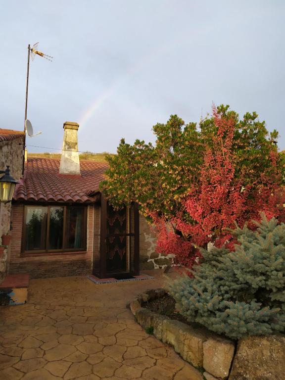 uma casa com uma árvore vermelha em frente em Casa Almenara em Almenara de Tormes