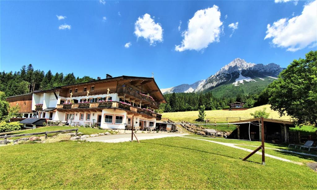 ein großes Gebäude mit einem Berg im Hintergrund in der Unterkunft Grubhof Appartements in Ellmau