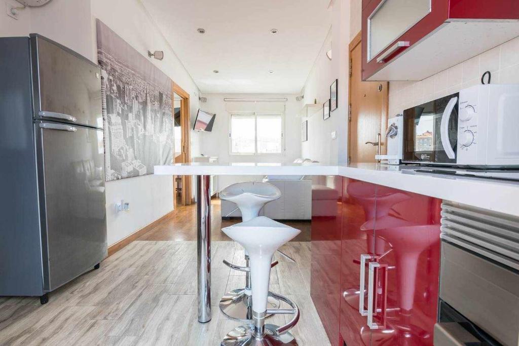 uma cozinha com um balcão branco e bancos vermelhos em Apartamento Céntrico LA CATEDRAL em Múrcia