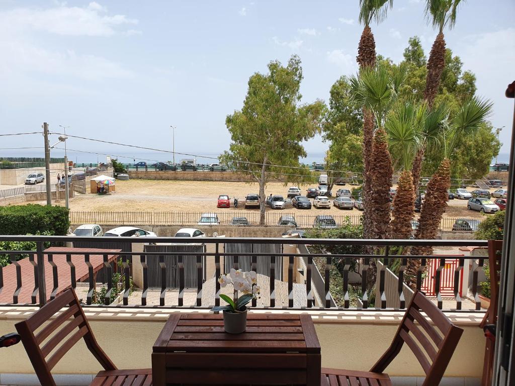 een balkon met een tafel en stoelen en een parkeerplaats bij Appartamento Ionios in Noto Marina