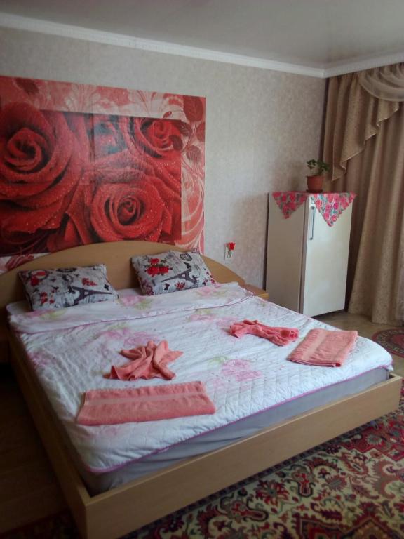 a bedroom with a bed with red roses on the wall at Стаи за гости Тамара in Ezerets