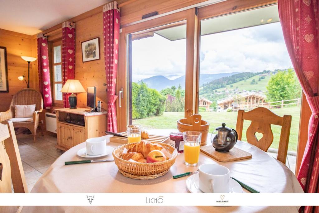 een tafel met een mand brood en een groot raam bij Sur Le Feug Appt 14 in Combloux