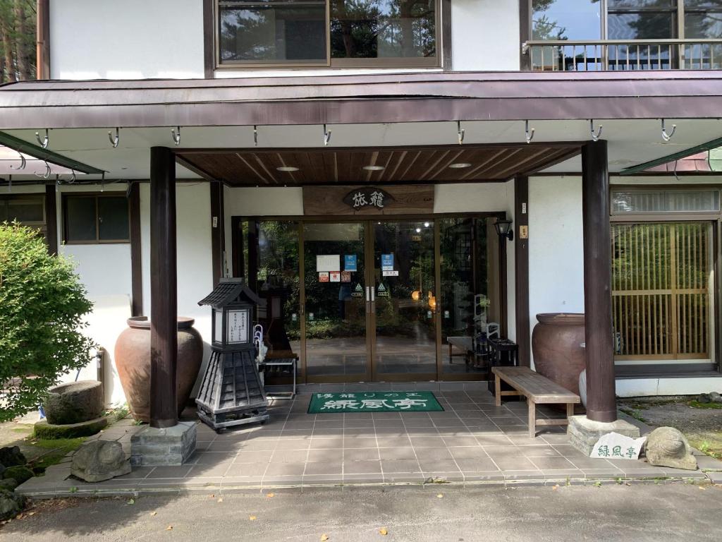 una puerta delantera de un edificio con un banco delante en ELE Hotel Onsen Ryokufutei en Kusatsu