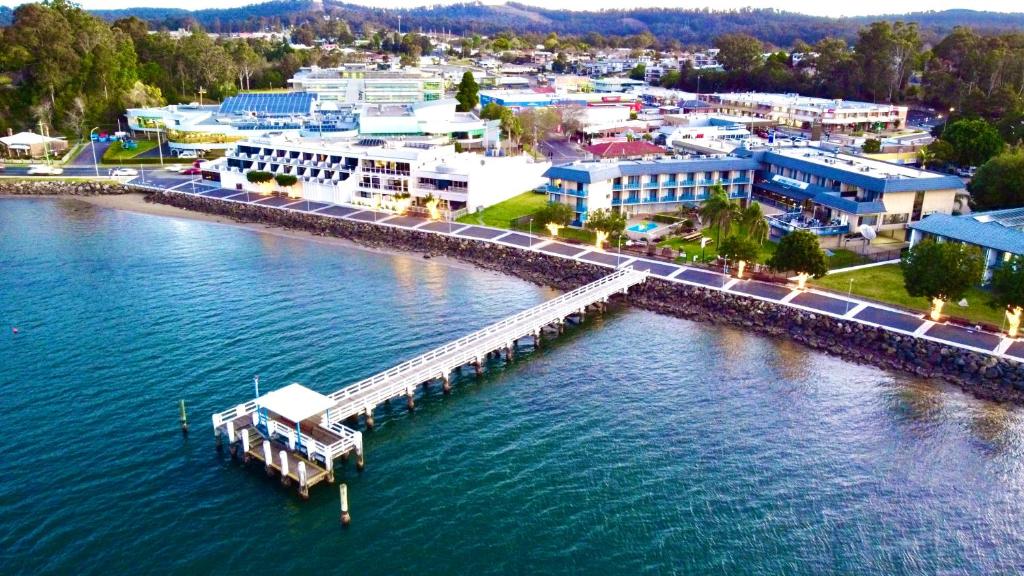 an aerial view of a city with a dock in the water at Zorba Waterfront Motel in Batemans Bay