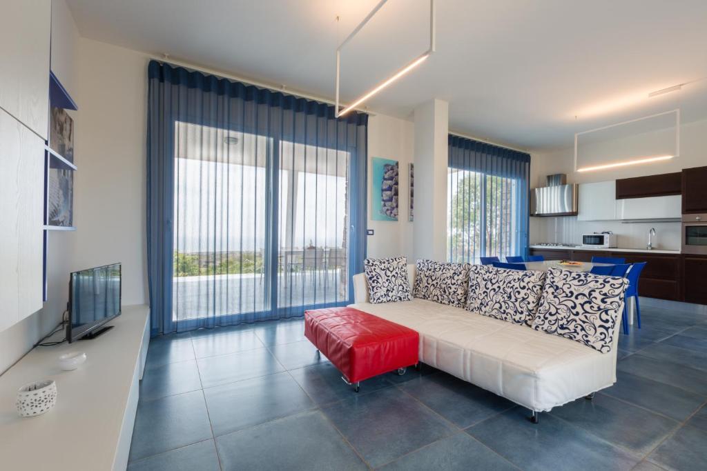 salon z białą kanapą i czerwonym stołkiem w obiekcie Fani Luxury Villas w mieście Torre Pali