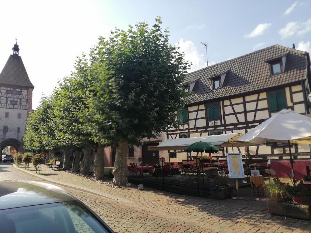 ein Gebäude mit Tischen und Sonnenschirmen auf einer Straße in der Unterkunft Gites Aux Fines Bulles d'Alsace SPA privatif en supplément in Bergheim