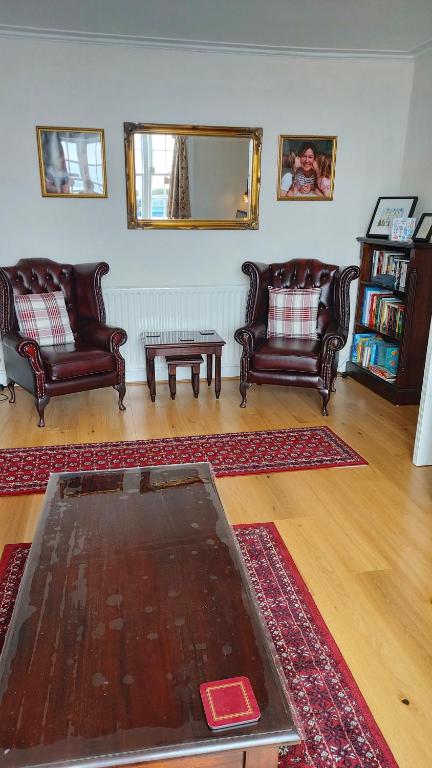 a living room with leather chairs and a coffee table at The Redcliff in Weymouth