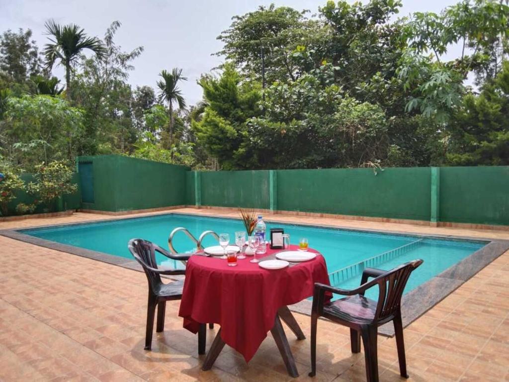 a table and chairs next to a swimming pool at Palm Era Resorts in Kushālnagar