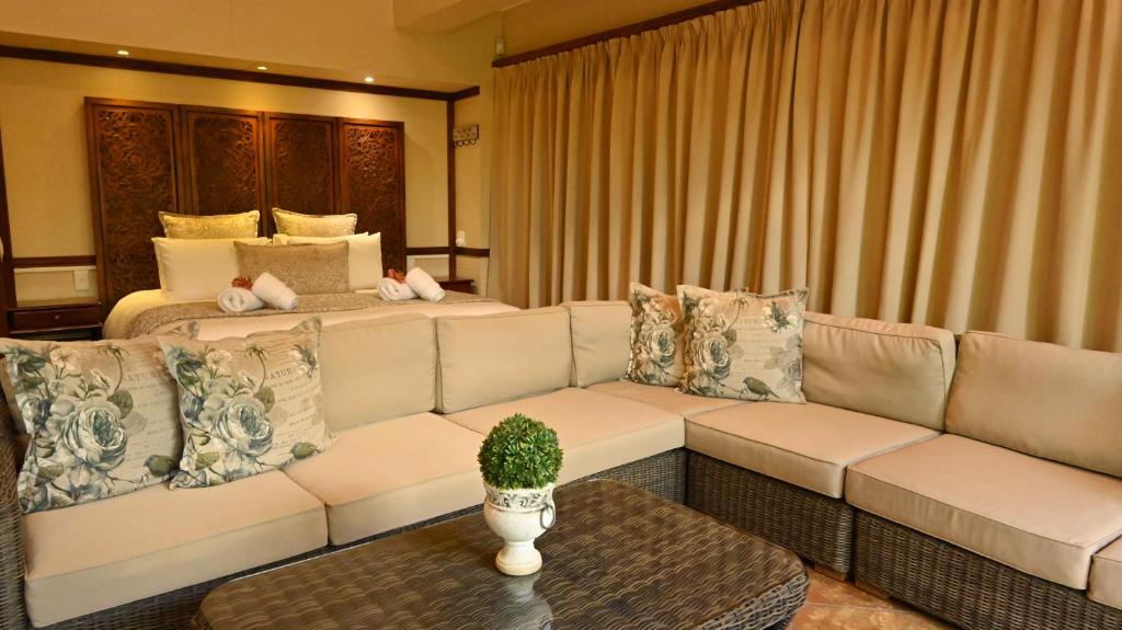 LUXURY EN-SUITE ROOM WITH LOUNGE @ 4 STAR GUEST HOUSE في ميدلبرغ: غرفة معيشة بها أريكة وسرير