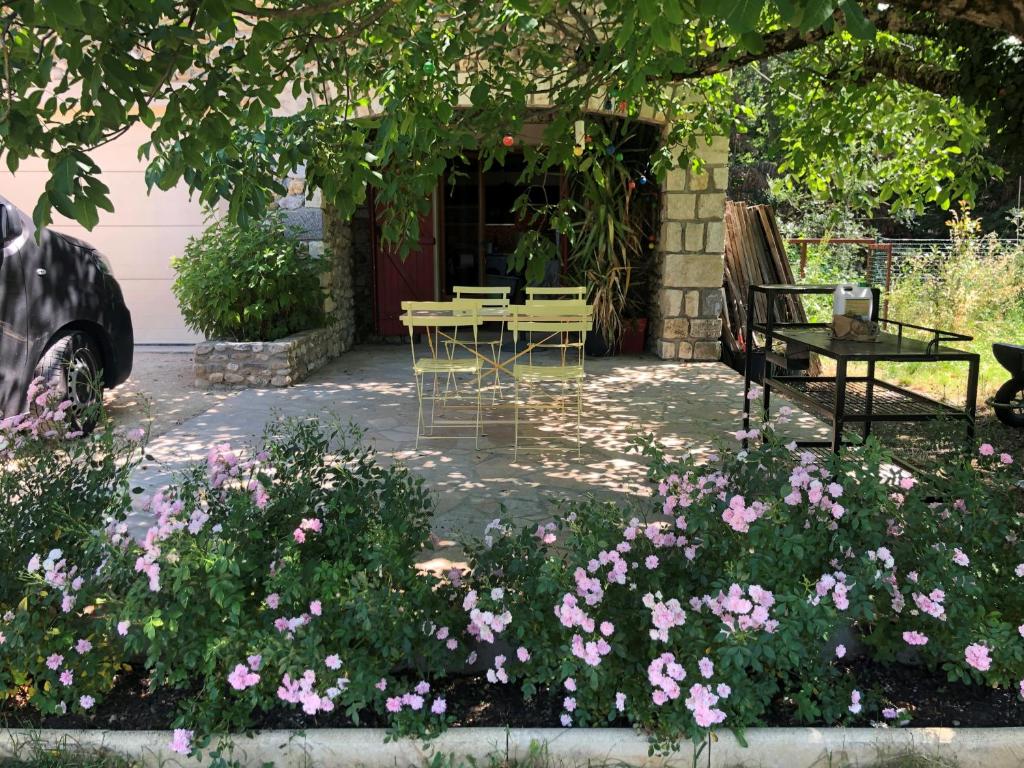 einen Garten mit rosa Blumen, einem Tisch und einer Bank in der Unterkunft Le Mas Charamèlia in Saint-Victor-de-Malcap