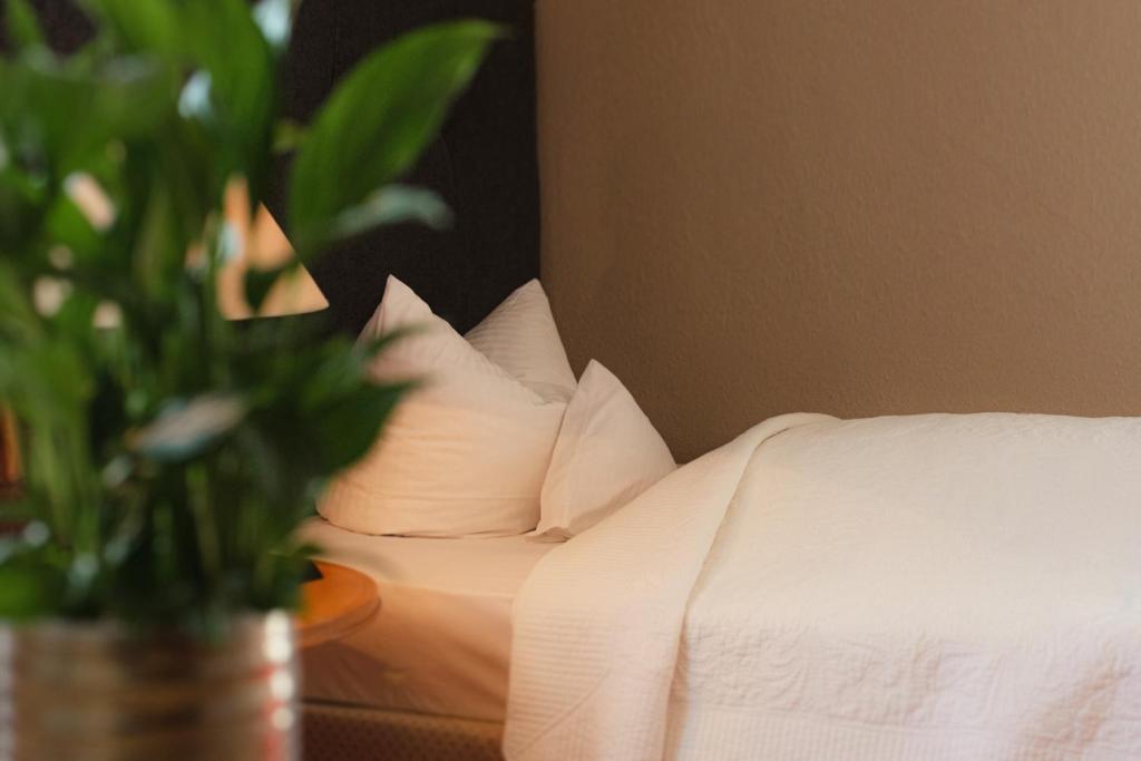 a white bed with pillows and a potted plant on a table at Hotel Das Kleine Ritz in Fellbach