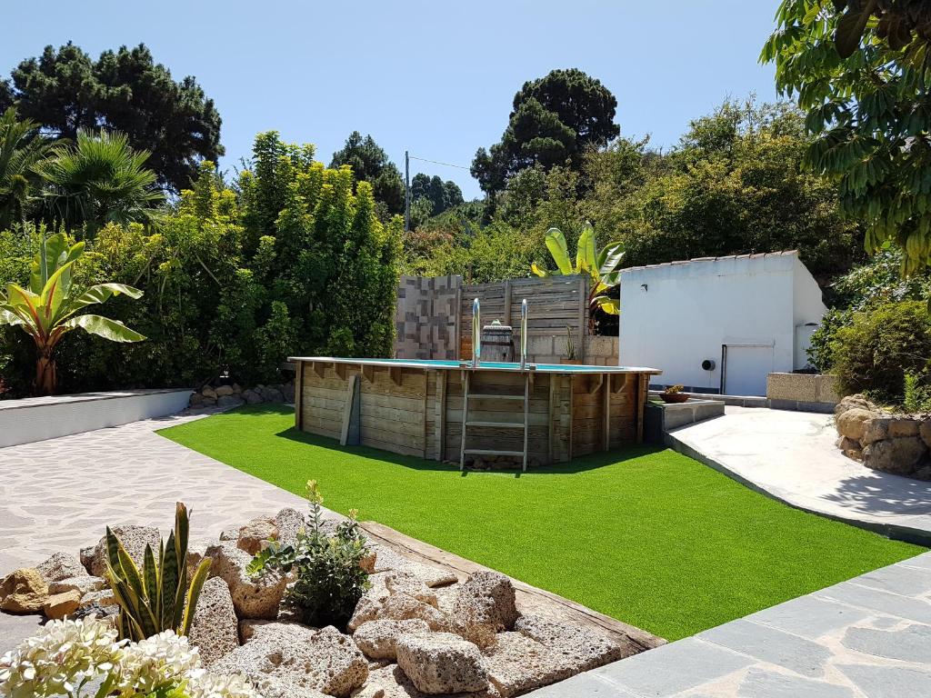 a garden with a pool and artificial grass at Finca Los Ciruelos Casas Rurales in Icod de los Vinos