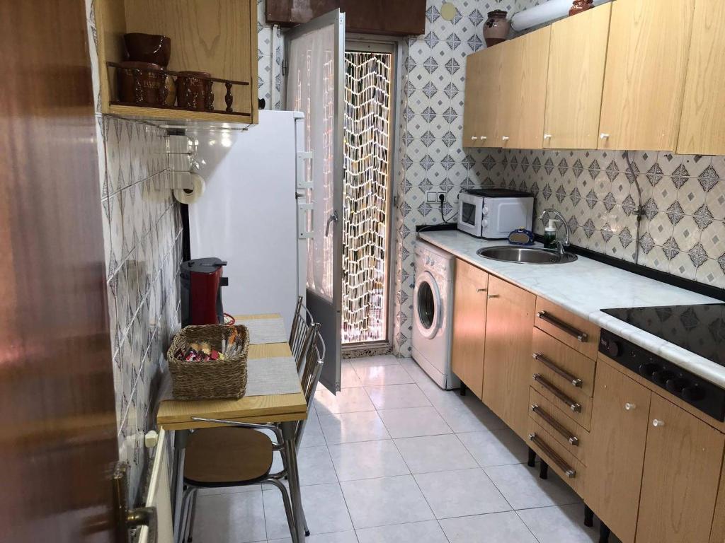 a kitchen with a refrigerator and a table and a sink at CASA LATY in La Fregeneda