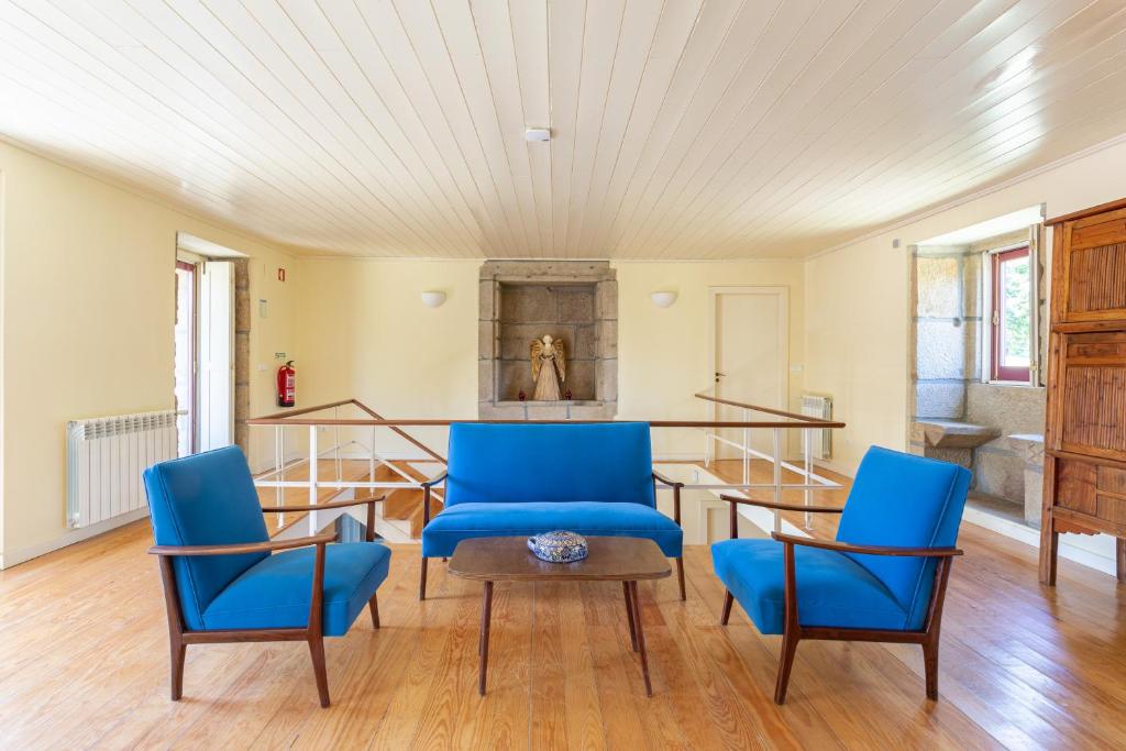 a living room with blue chairs and a table at Quinta de Fermil - Casas in Vouzela