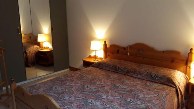 a bedroom with a bed with two lamps and a mirror at Casa vacanza Terry a Sella Nevea in Sella Nevea