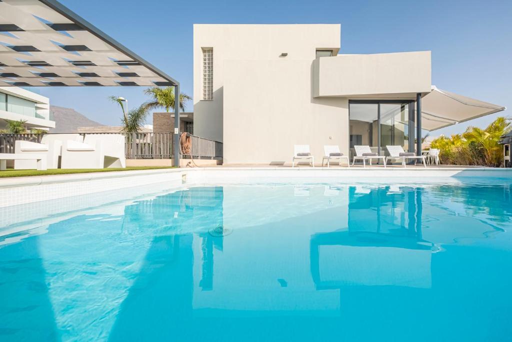 a swimming pool in front of a villa at Villa Alisios Golf Luxury Tenerifesummervillas Heated pool in Adeje