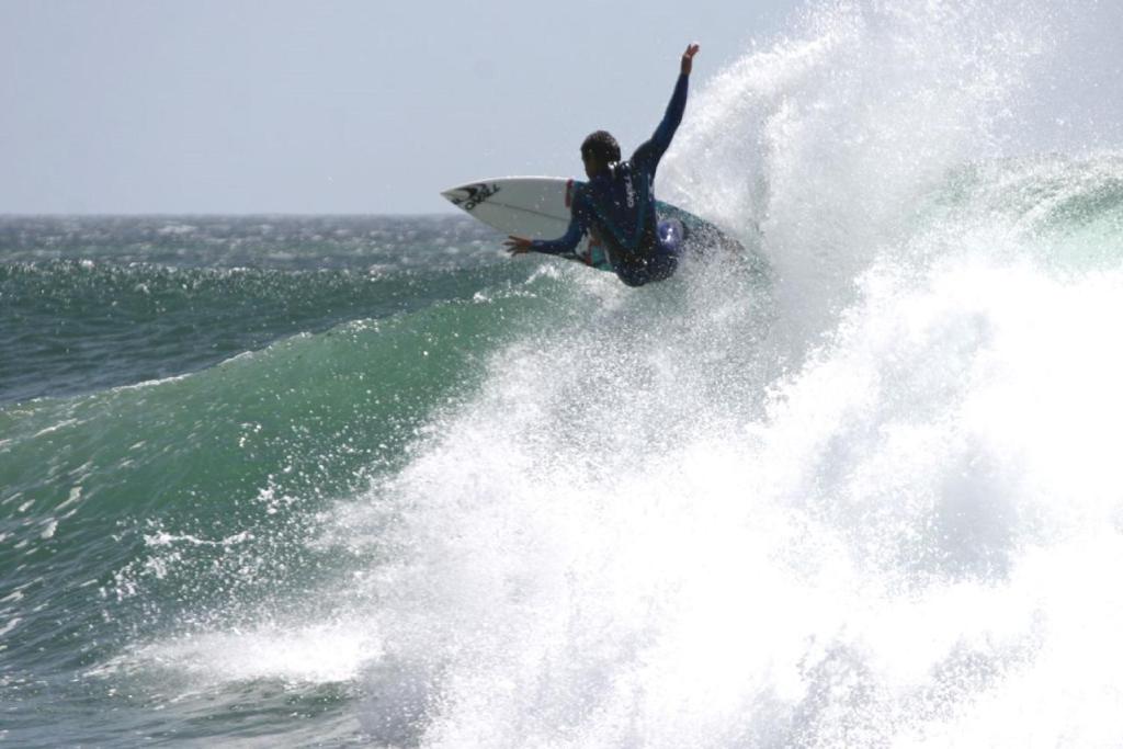 a man riding a wave on a surfboard in the ocean at Pure Flor de Esteva in Vila do Bispo