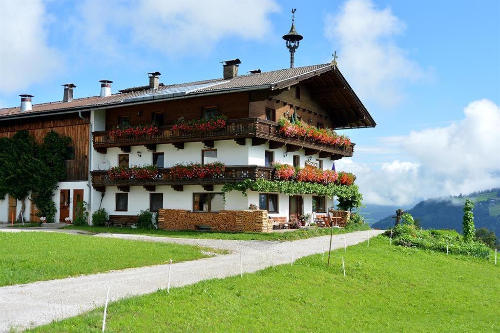 a building on a hill with flowers on it at Embacher Marianne - Rotharlhof in Hopfgarten im Brixental